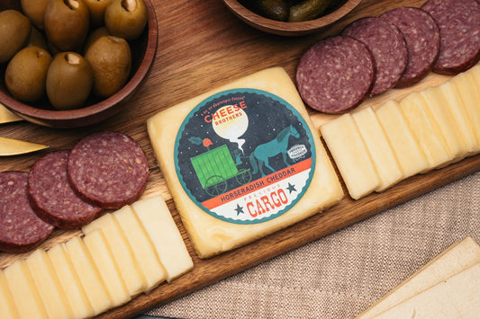 Slices of Precious Cargo Horseradish Cheddar cheese from Cheese Brothers, Inc., showing its rich texture and horseradish flavor.