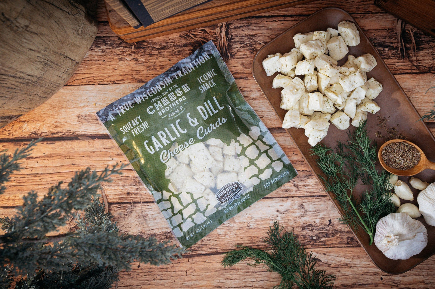 Garlic and dill cheese curds from Cheese Brothers, Inc., showing a pack of fresh cheese curds with herbs and garlic visible.
