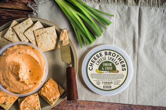 Creamy Onion and Chive Cheese Spread by Cheese Brothers, Inc. in a jar with visible herbs and cheese texture.