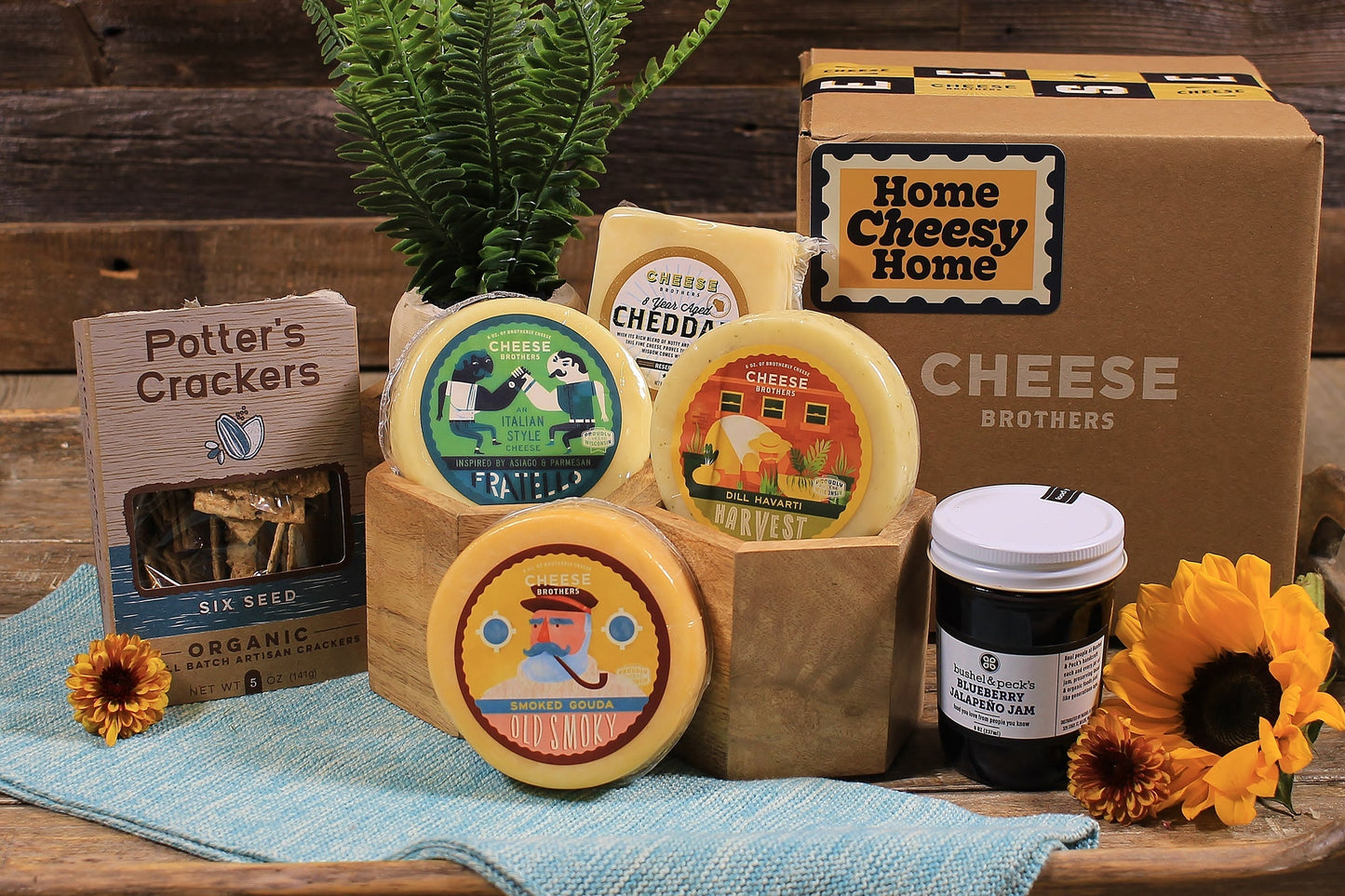 Housewarming gift basket from Cheese Brothers, Inc. with assorted cheeses, crackers, and snacks in a decorative bundle.