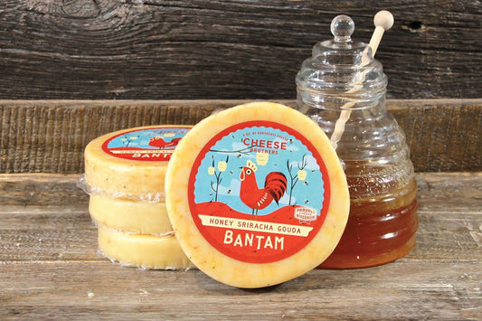 Creamy Gouda cheese from Cheese Brothers, Inc. with honey and sriracha flavor, showcasing a wedge of Honey Sriracha Gouda.