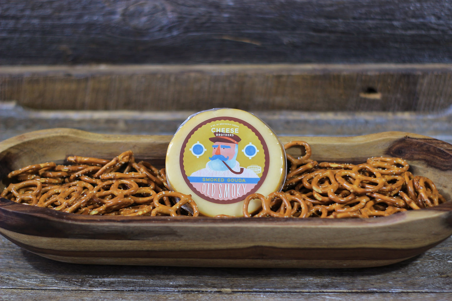 Smoked Gouda cheese by Cheese Brothers, Inc., showing a block of rich, smoked Gouda cheese with a smooth, golden-brown rind.
