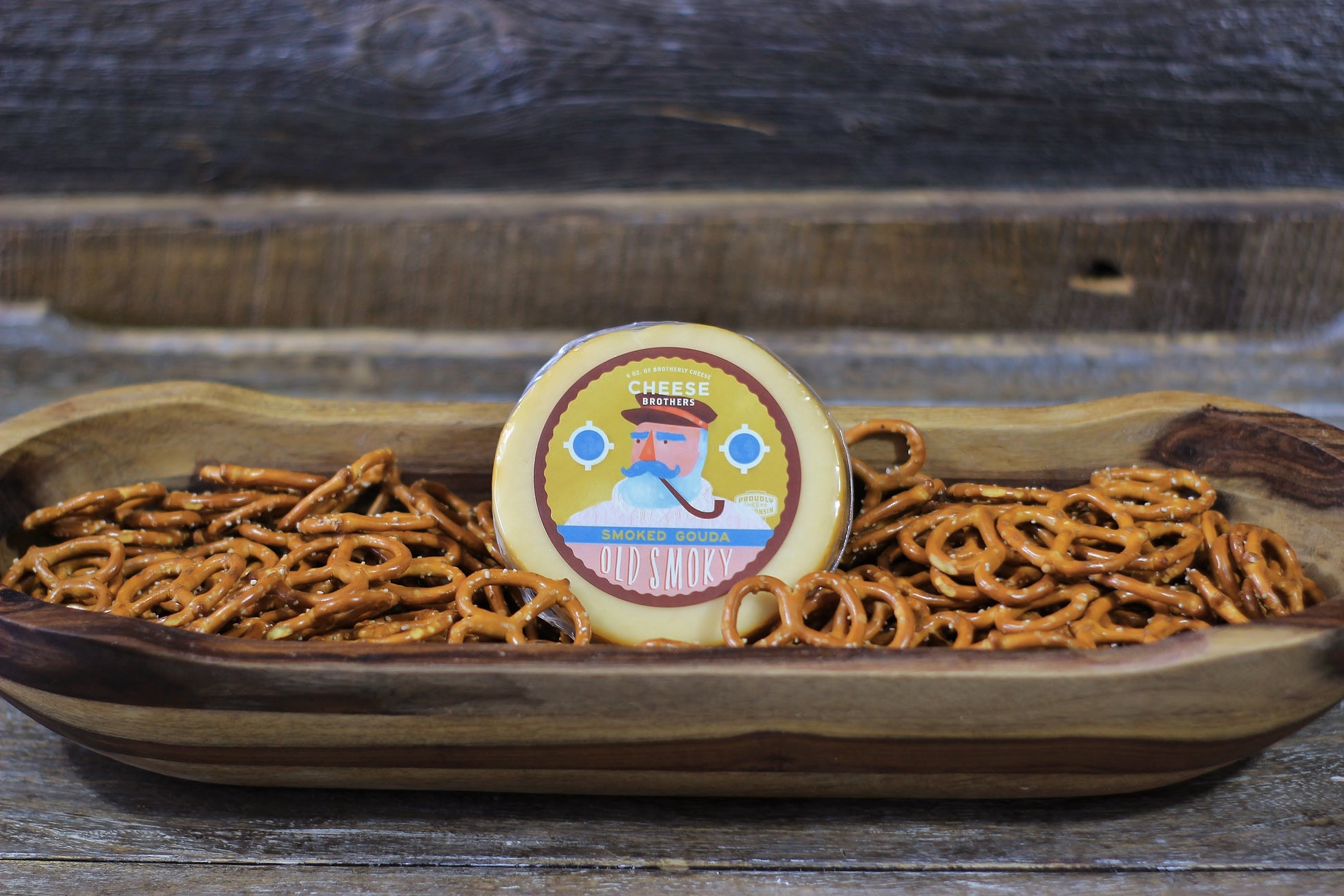 Smoked Gouda cheese by Cheese Brothers, Inc., showing a block of rich, smoked Gouda cheese with a smooth, golden-brown rind.
