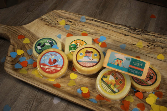 Cheese Brothers Inc. cheese and thank you gift box with assorted cheeses, crackers, and a thank you note on a wooden surface.
