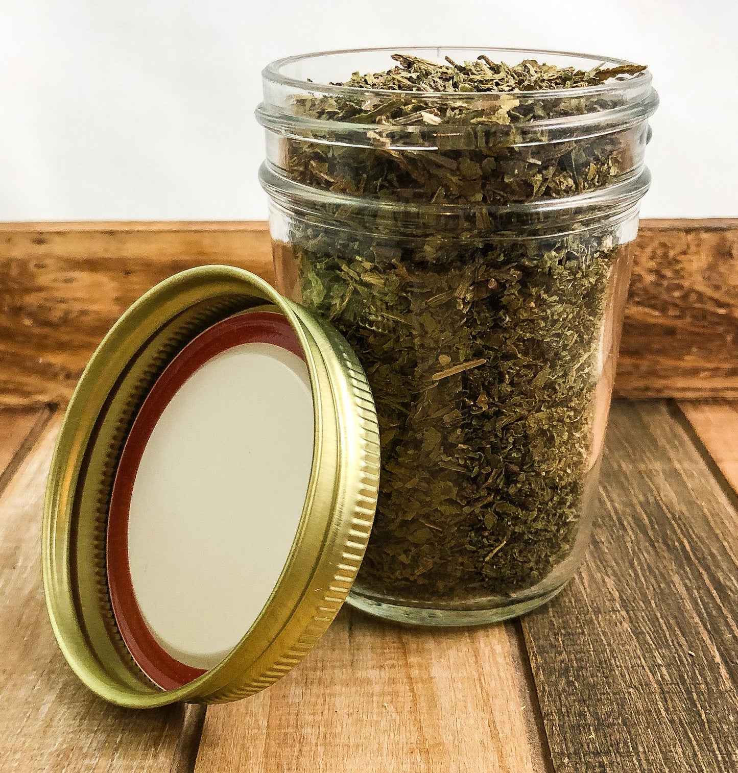 Small herbal jar with dried comfrey herbs from HerbalRoseApothecary, featuring a white lid and wooden accents.