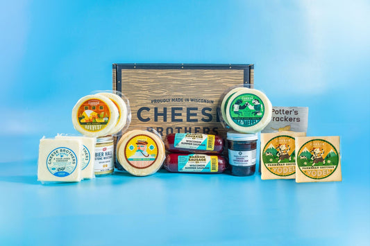 Deluxe Charcuterie Pack from Cheese Brothers, Inc. featuring an assortment of cured meats, cheeses, and accompaniments arranged on a wooden board.