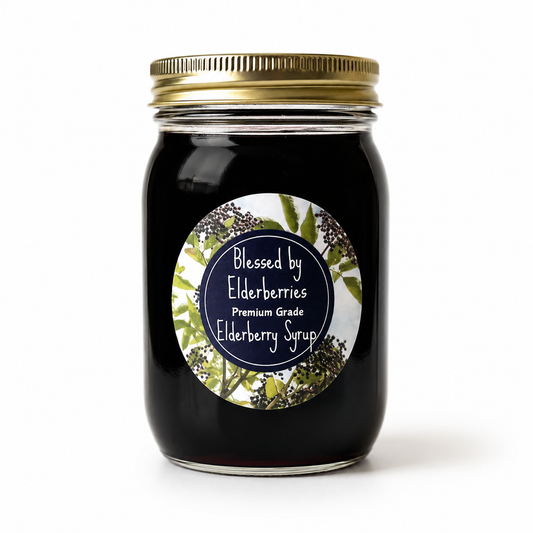 Bottle of Blessed by Elderberries elderberry syrup with fresh elderberries and herbs in a glass jar on a wooden surface.