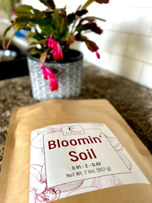 Elm Dirt Bloomin' Soil organic flower booster bag showing 2 lbs of soil for bigger, longer-lasting blooms in garden plants.