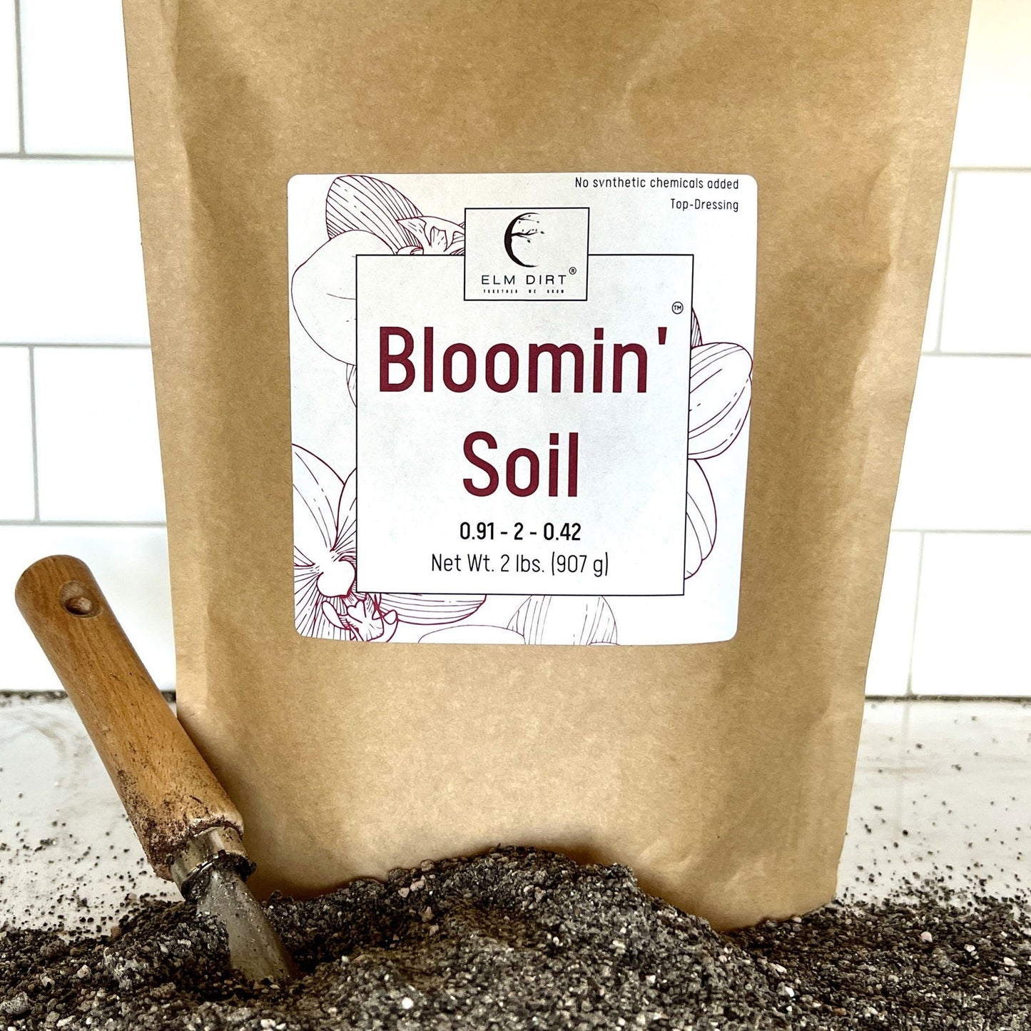 Elm Dirt Bloomin' Soil in a 2-lb bag, organic soil for plants, with visible soil texture and branding on the packaging.