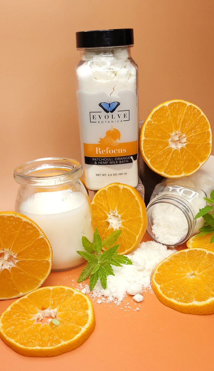 Evolve Botanica Milk Bath Refocus with patchouli, orange, and hempseed oil, shown in a soothing, natural bath setting.