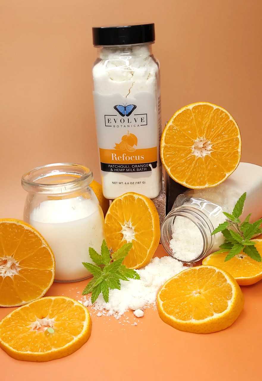 Evolve Botanica Milk Bath Refocus with Patchouli, Orange, and Hempseed Oil in a calming bath setting.