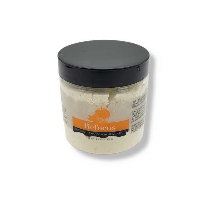 Mini Evolve Botanica Milk Bath Refocus with patchouli, orange, and hempseed oil, featuring a calming bath product in a natural setting.