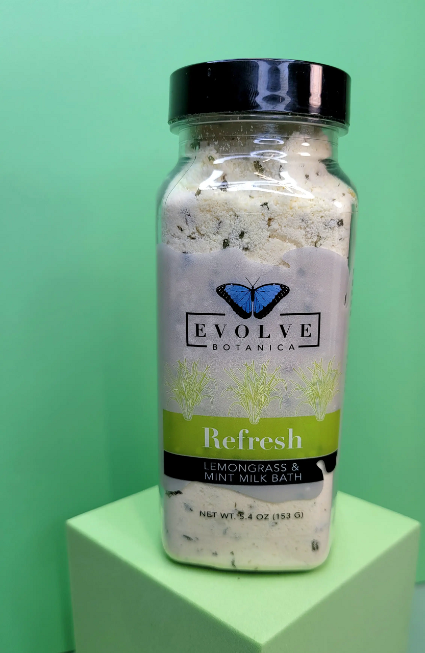 Evolve Botanica Milk Bath Refresh with lemongrass and mint, showing a soothing milk bath product with fresh herbs.