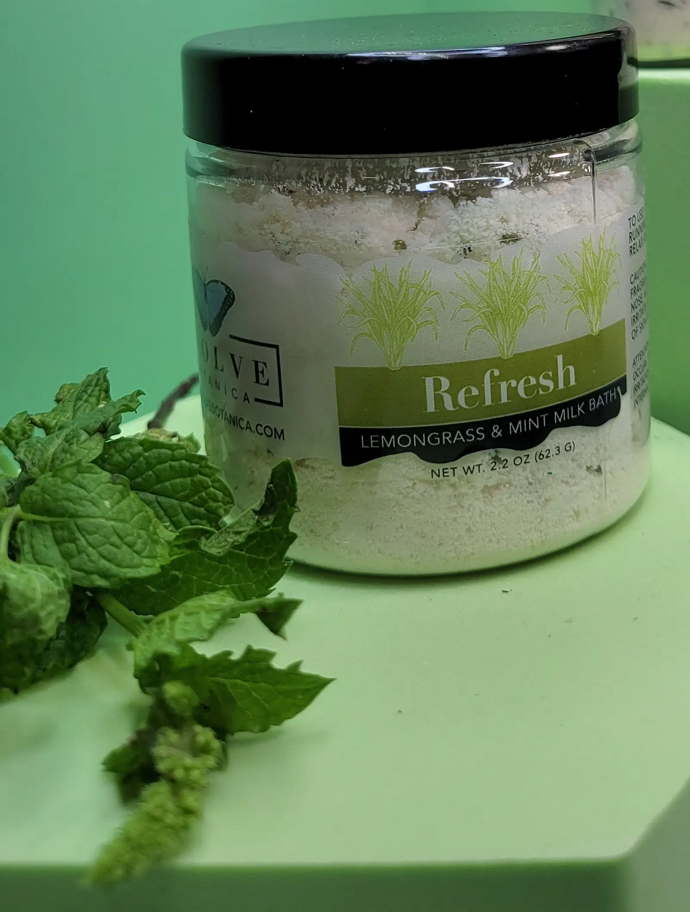 Mini Milk Bath by Evolve Botanica, Refresh scent with lemongrass and mint, showing the product container and fresh ingredients.
