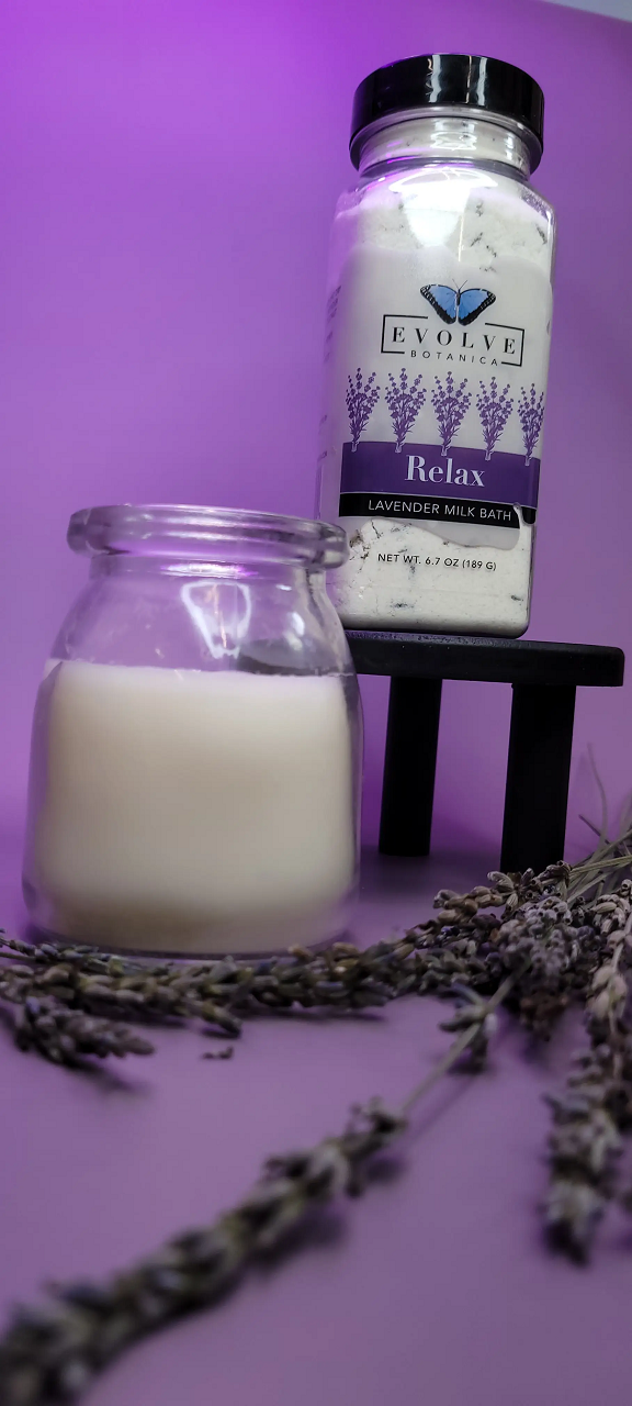 Evolve Botanica Relax Lavender Milk Bath in a clear jar with lavender flowers and creamy milk bath powder inside.