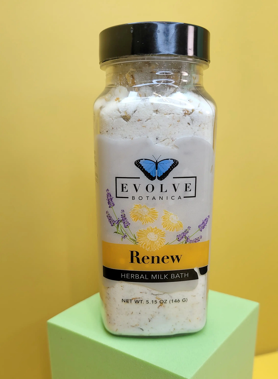 Evolve Botanica Milk Bath Renew Herbal with natural herbs in a relaxing bath experience, shown in a clear container with herbs.
