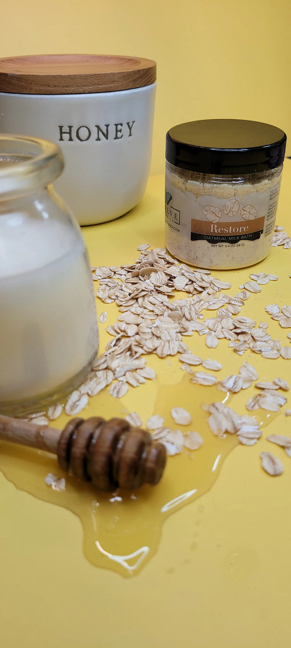Mini Evolve Botanica Milk Bath Restore with Oatmeal, showing a soothing powder blend in a clear jar with a natural setting.