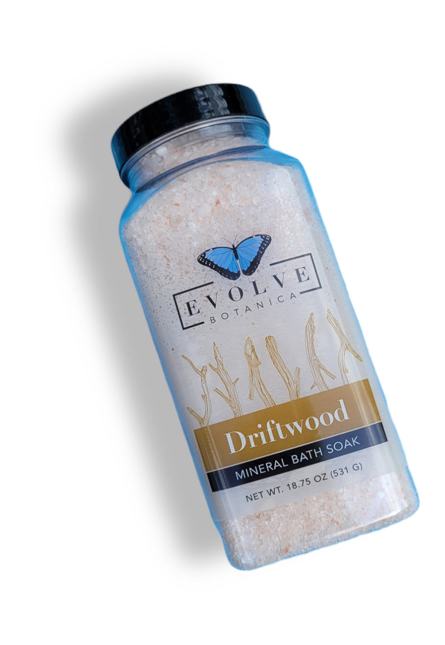 Evolve Botanica Mineral Soak Driftwood bath salt in a clear jar with driftwood pieces and natural sea minerals for relaxing bath.