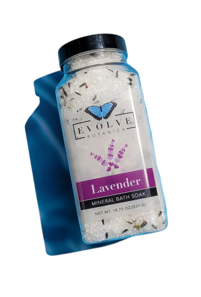 Evolve Botanica Mineral Soak Lavender Spa bath salt in a jar, with lavender flowers and relaxing bath setting