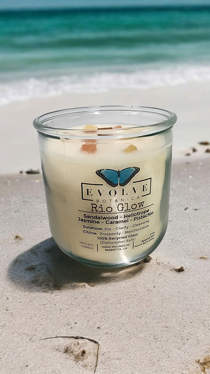 Evolve Botanica Rocks Candle Rio Glow with wood wick, sunstone, citrine gemstones, and soy wax in a decorative glass jar.