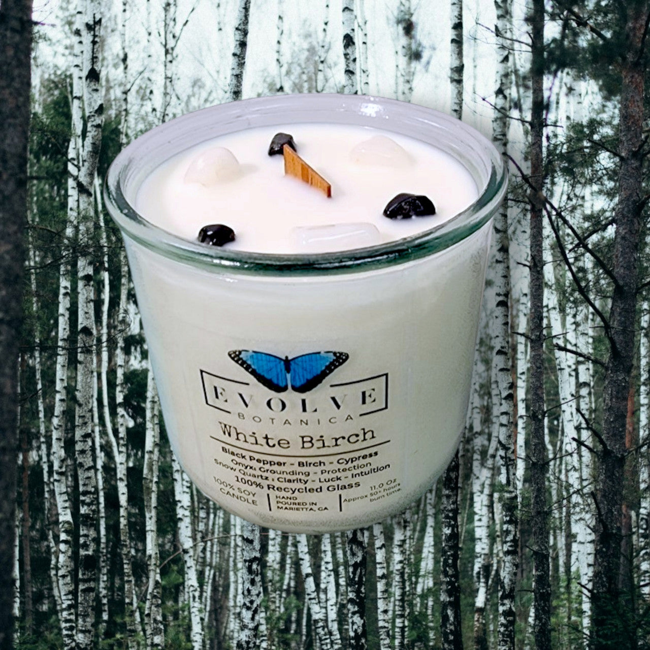 White Birch Rocks Candle by Evolve Botanica with wood wick, snow quartz, and onyx gemstones in a soy candle container.