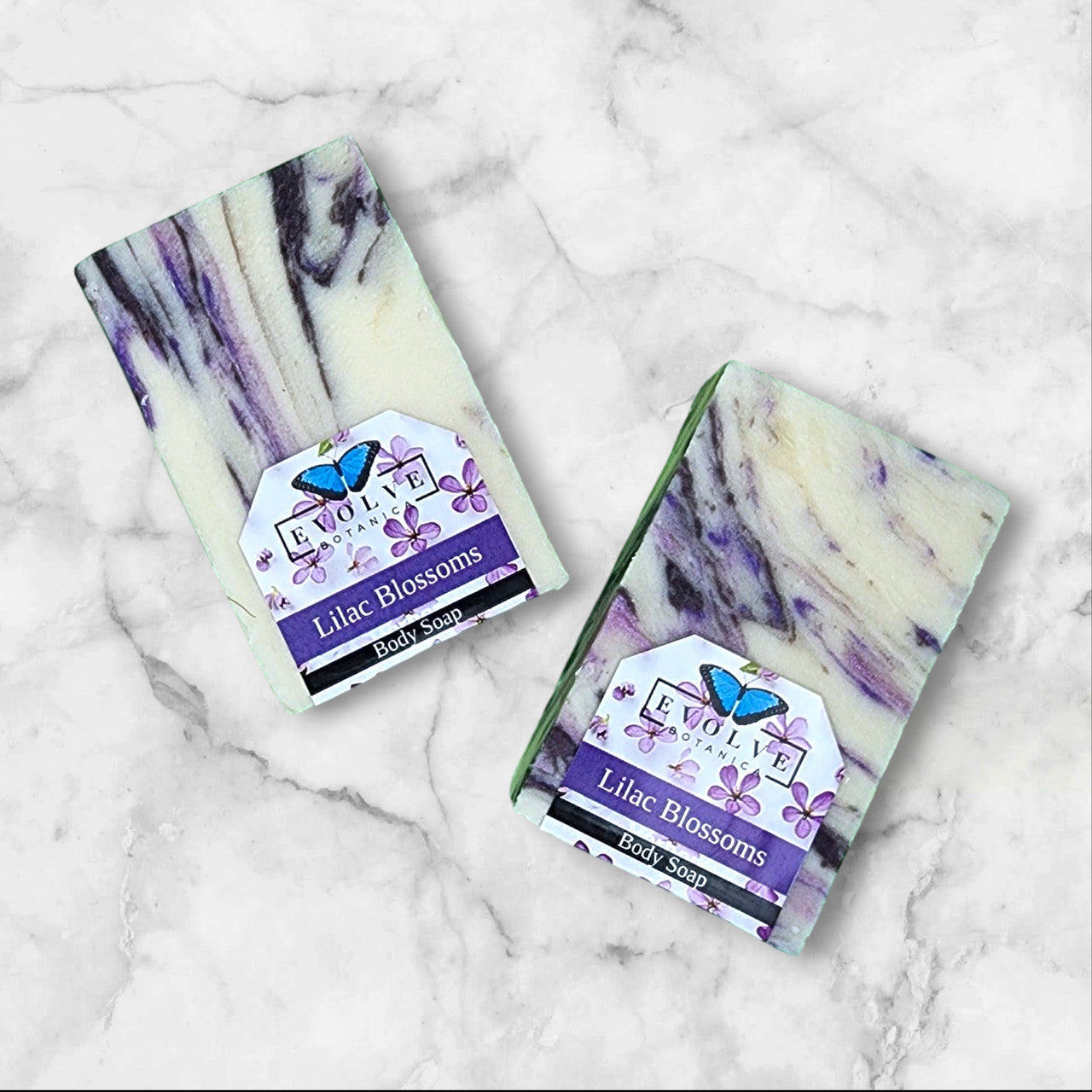 Evolve Botanica Seasonal Soap with Lilac Blossoms, featuring a bar of soap with lilac flower accents and floral packaging.