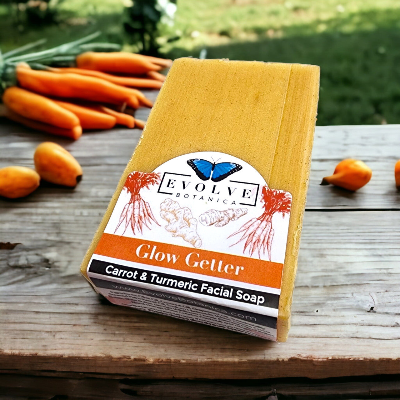 Evolve Botanica Glow Getter facial soap with carrot, turmeric, and honey for radiant skin, displayed in a natural setting.