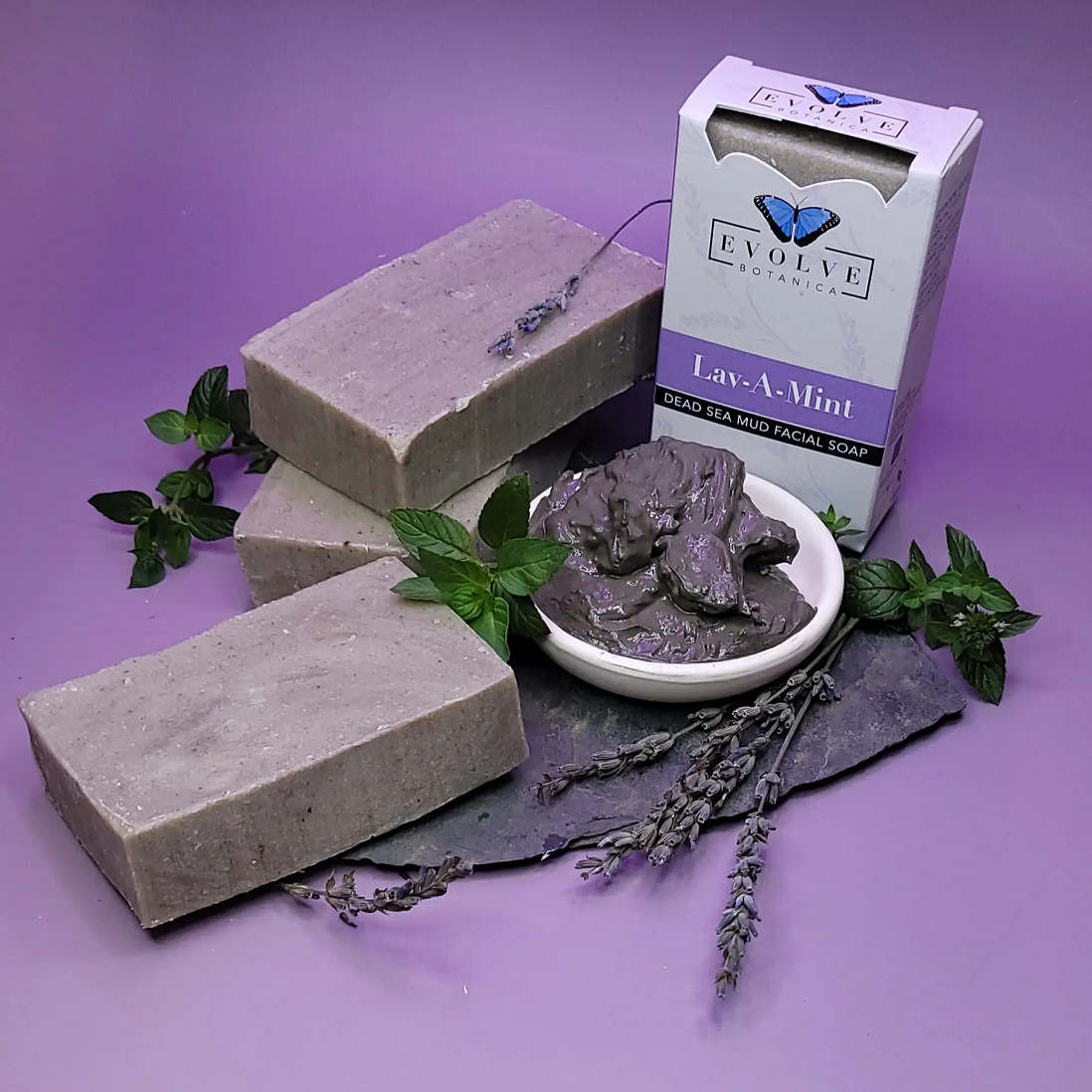 Evolve Botanica Lav-A-Mint Dead Sea Mud Facial Soap in a clear glassine bag, showing the soap's textured surface and minty color.