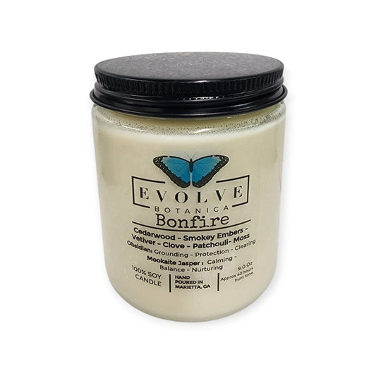 Evolve Botanica 9oz jam jar soy candle with wood wick in Obsidian and Mookaite crystals, featuring a bonfire scent.