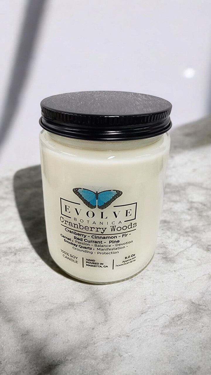 Evolve Botanica 9oz jam jar crystal soy candle in Cranberry Woods with garnet and smokey quartz accents, natural wood wick.
