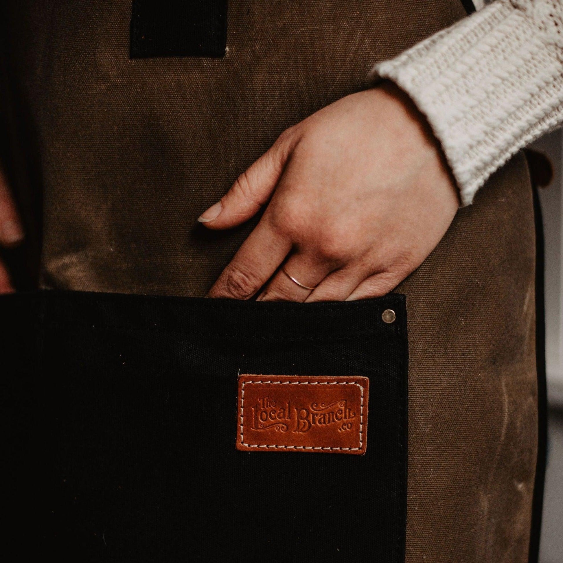 Waxed canvas apron from The Local Branch, USA made, shown with adjustable straps and durable stitching in a fall-themed setting.