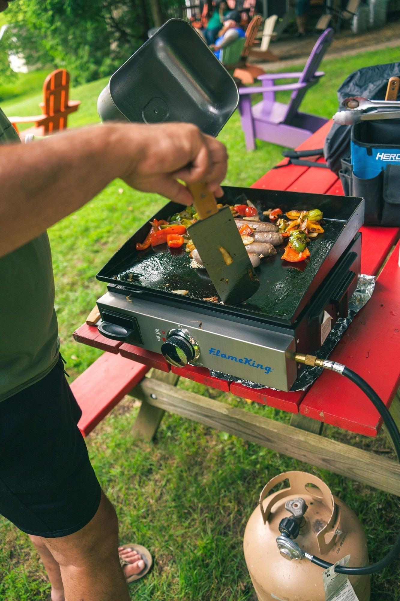 Flame King flat top portable propane cast iron grill griddle for camping, showing a sturdy black cast iron cooking surface.