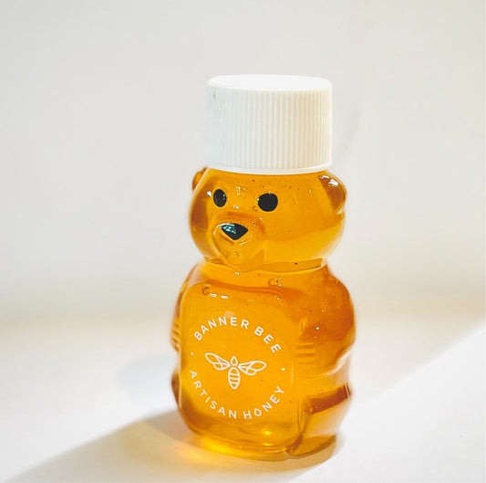 Mini honey bear bottle filled with raw honey by BannerBee Company LLC, showcasing the cute bear-shaped container.