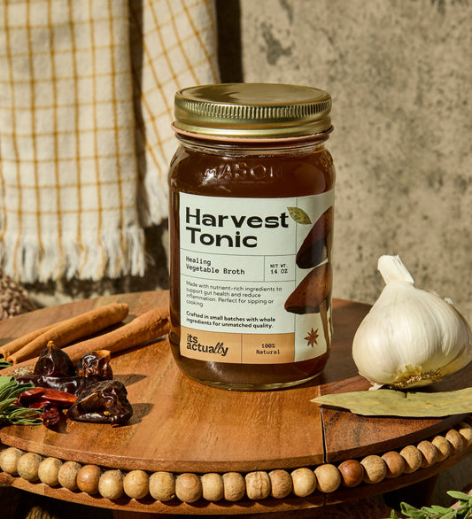 Three 14oz jars of Its Actually Co. Healing Vegetable Broth beverage, featuring fresh vegetable ingredients in glass jars.