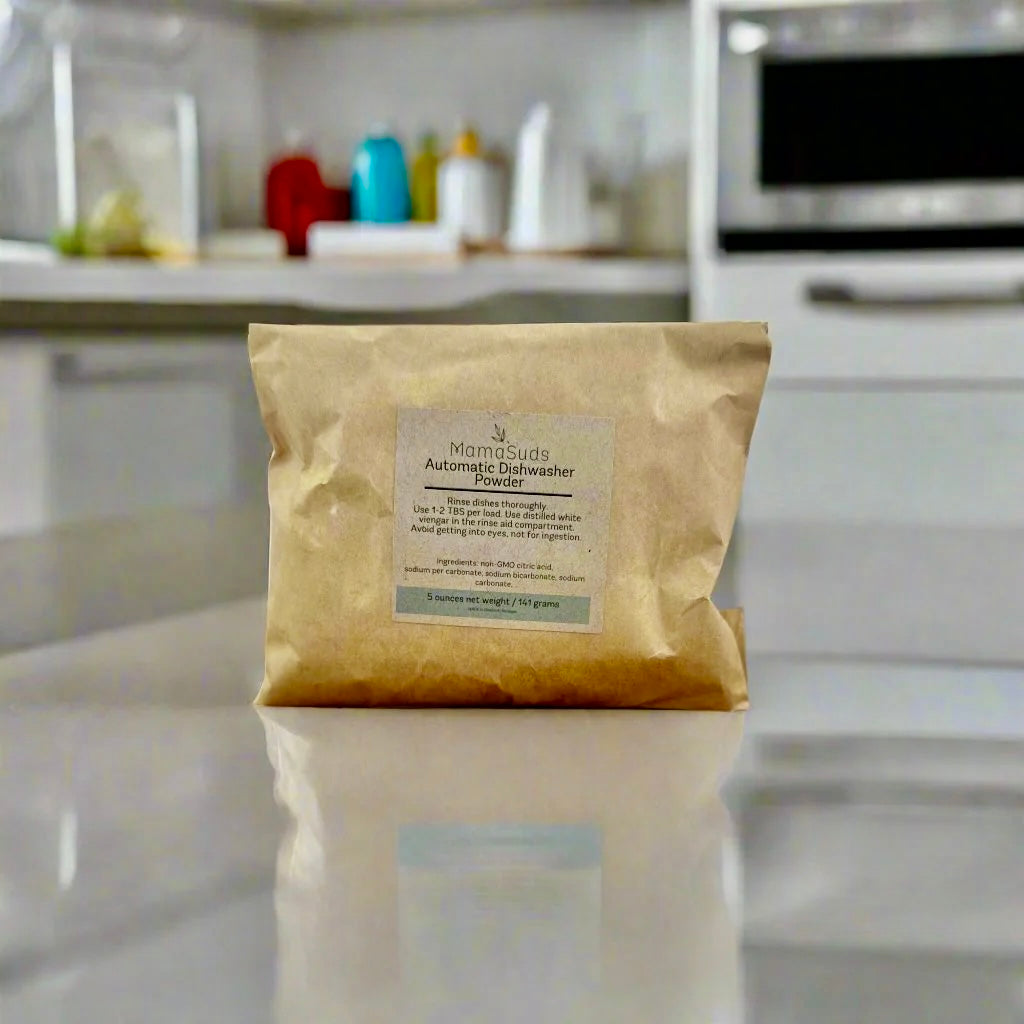 Automatic dishwasher powder sample by MamaSuds for household cleaning, shown in a clear container with white powder.