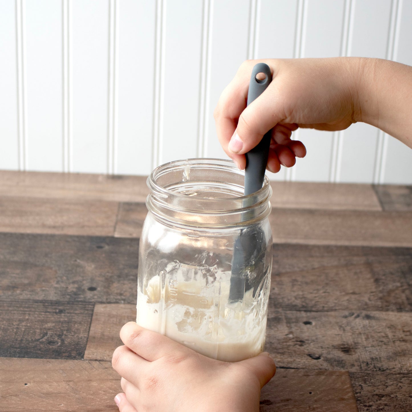Charcoal gray silicone jar scraper by Mason Jar Lifestyle in use, ideal for cleaning 32oz wide-mouth jars and sourdough starter.