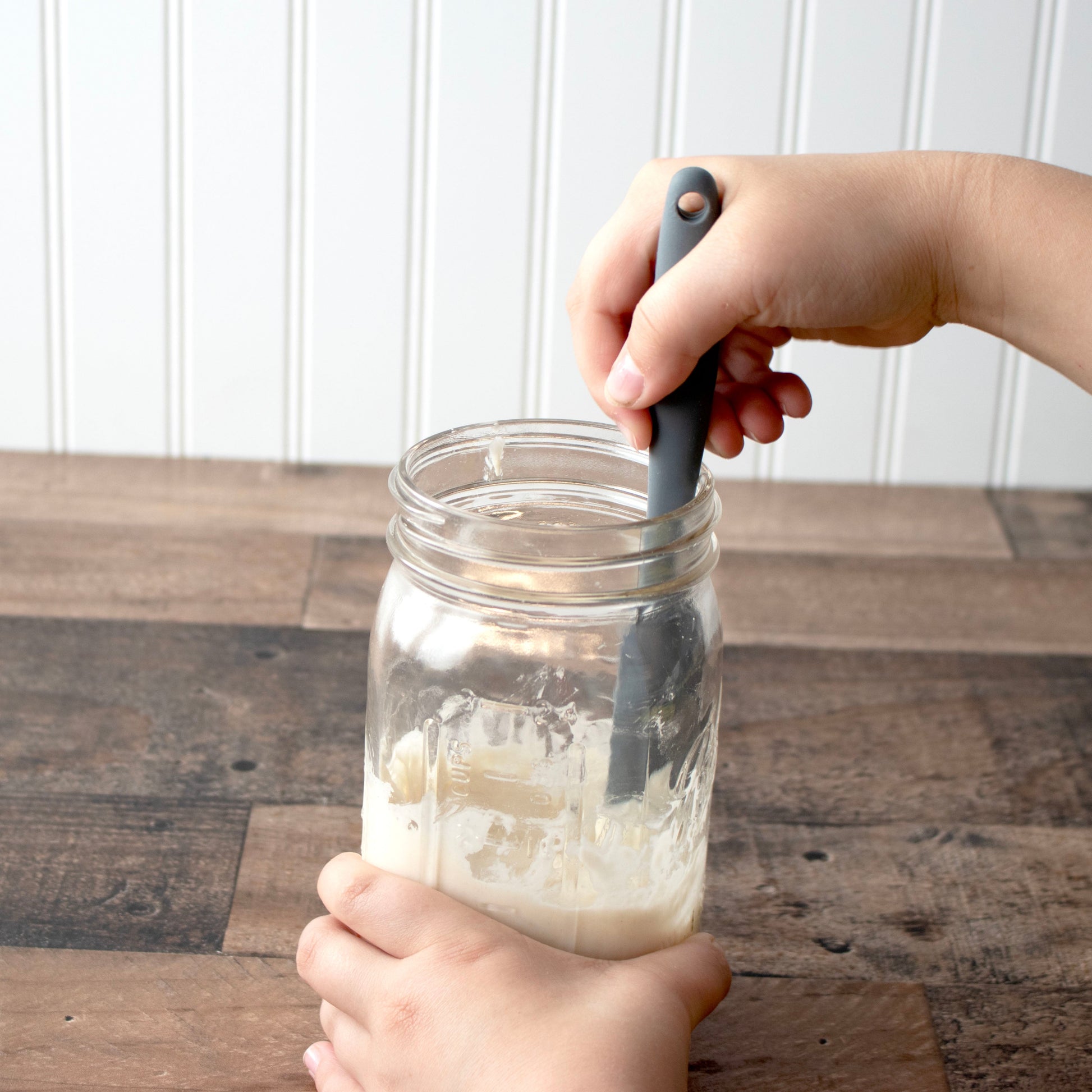 Charcoal gray silicone jar scraper by Mason Jar Lifestyle in use, ideal for cleaning 32oz wide-mouth jars and sourdough starter.