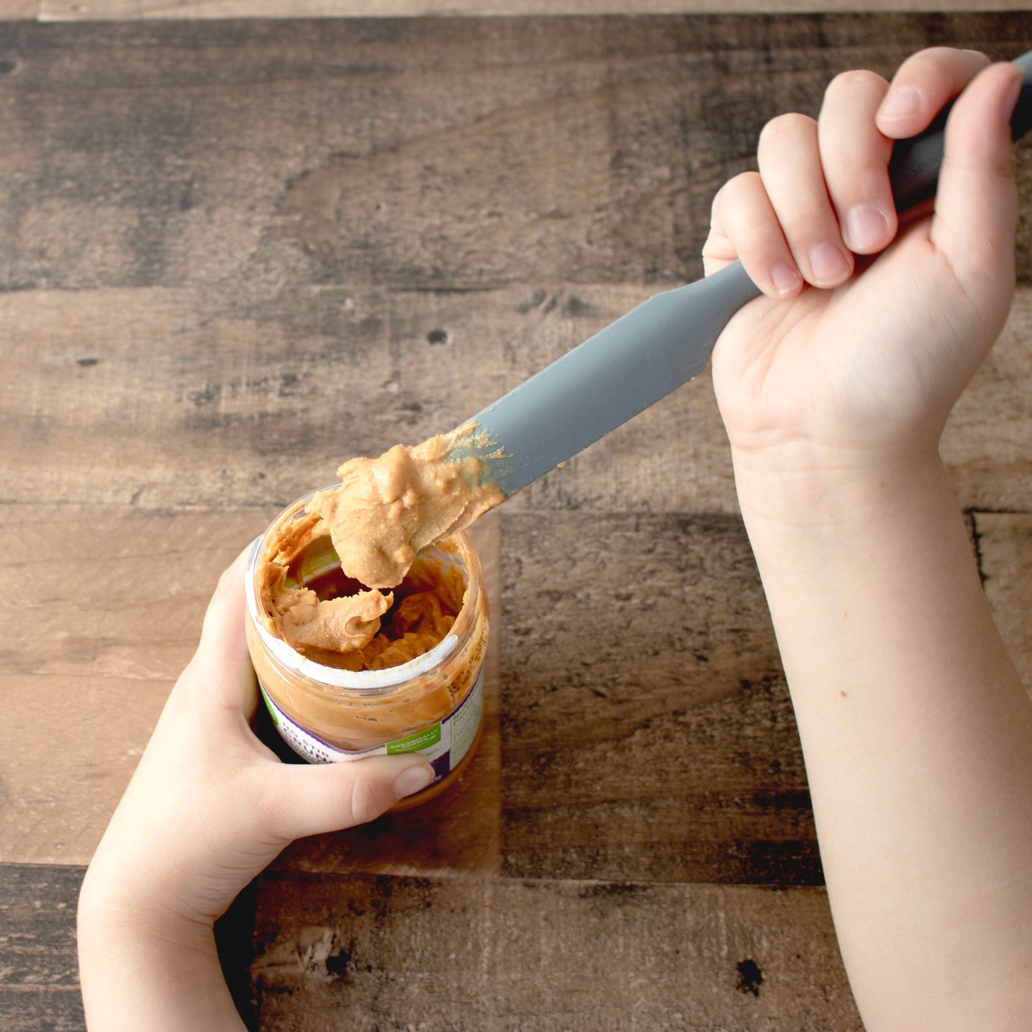 Charcoal gray silicone jar scraper from Mason Jar Lifestyle used to scoop peanut butter from a jar.