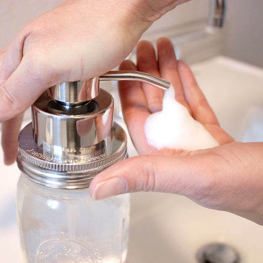 Stainless steel Mason Jar Lifestyle foaming soap pump dispenser on a mason jar with a mirror chrome finish, in use.