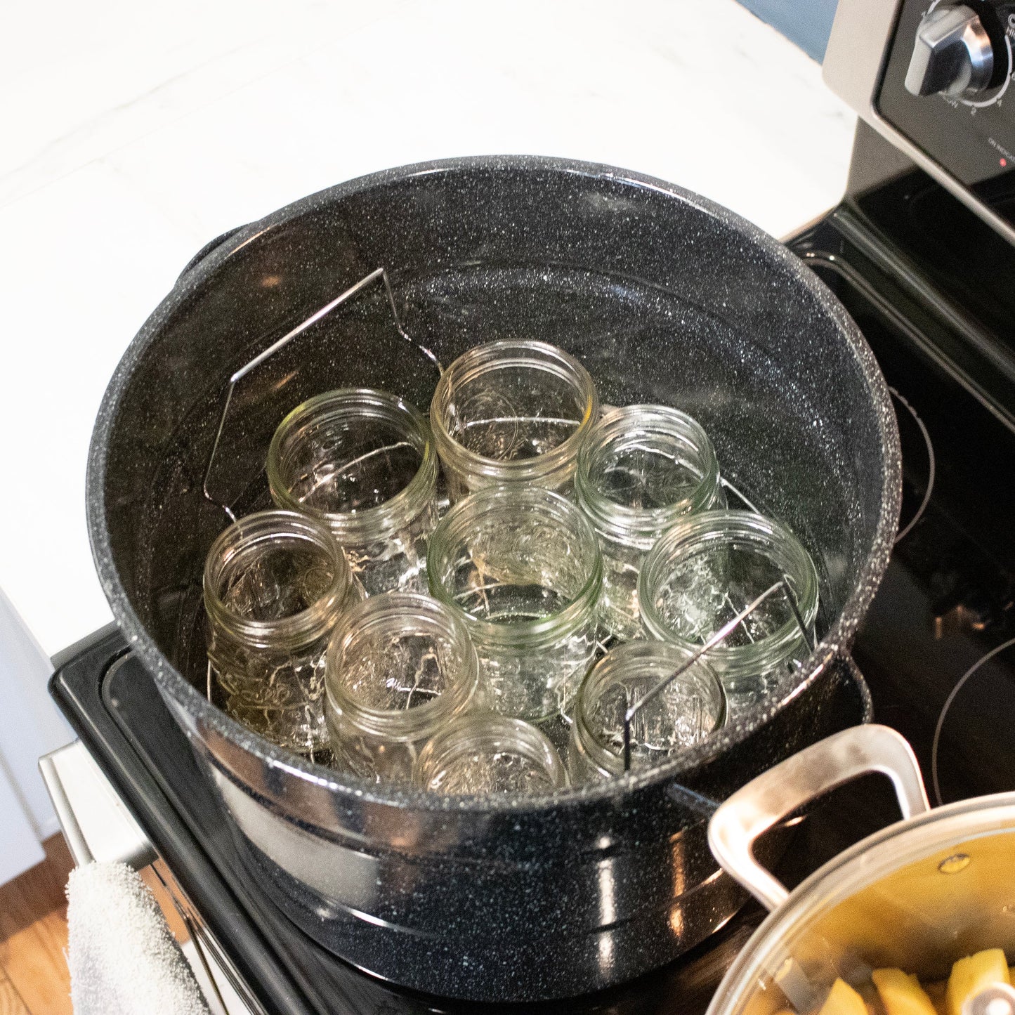 Stainless steel Water Bath Canning Rack by Mason Jar Lifestyle, shown supporting jars in a water bath canning setup.