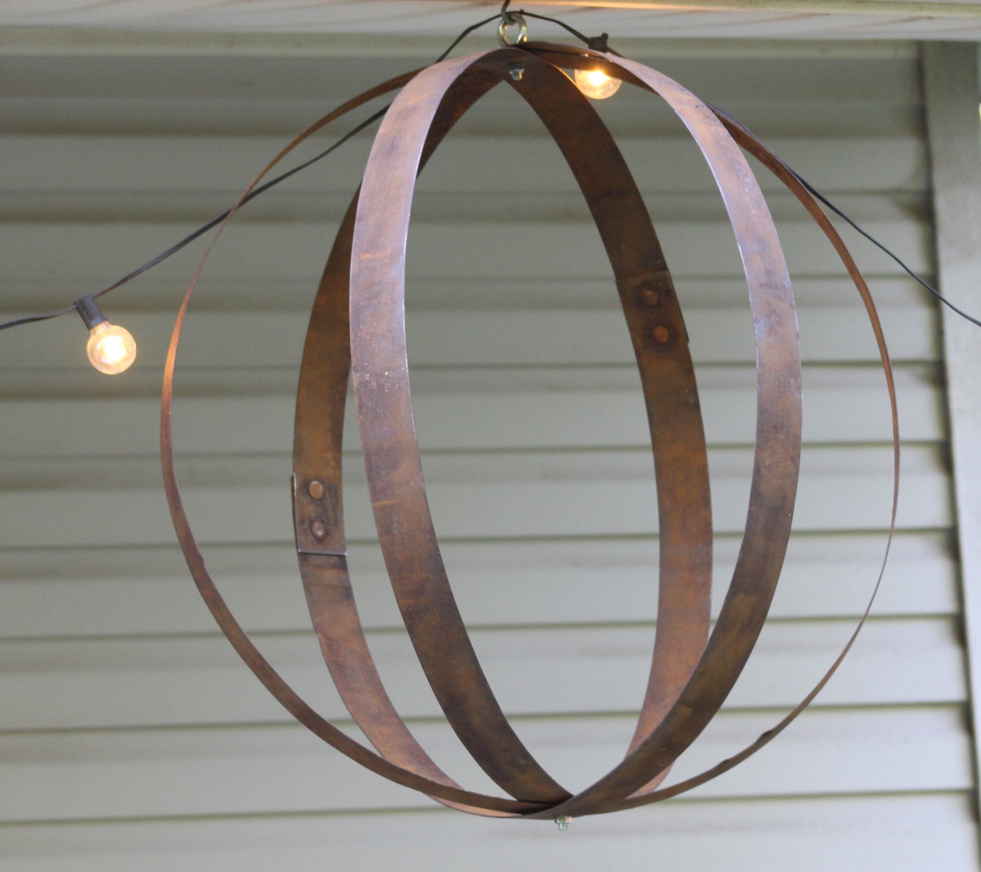 Rustic outdoor hanging plant holder made from reclaimed whiskey barrel rings, crafted by AmishToyBox.com, for garden decor.