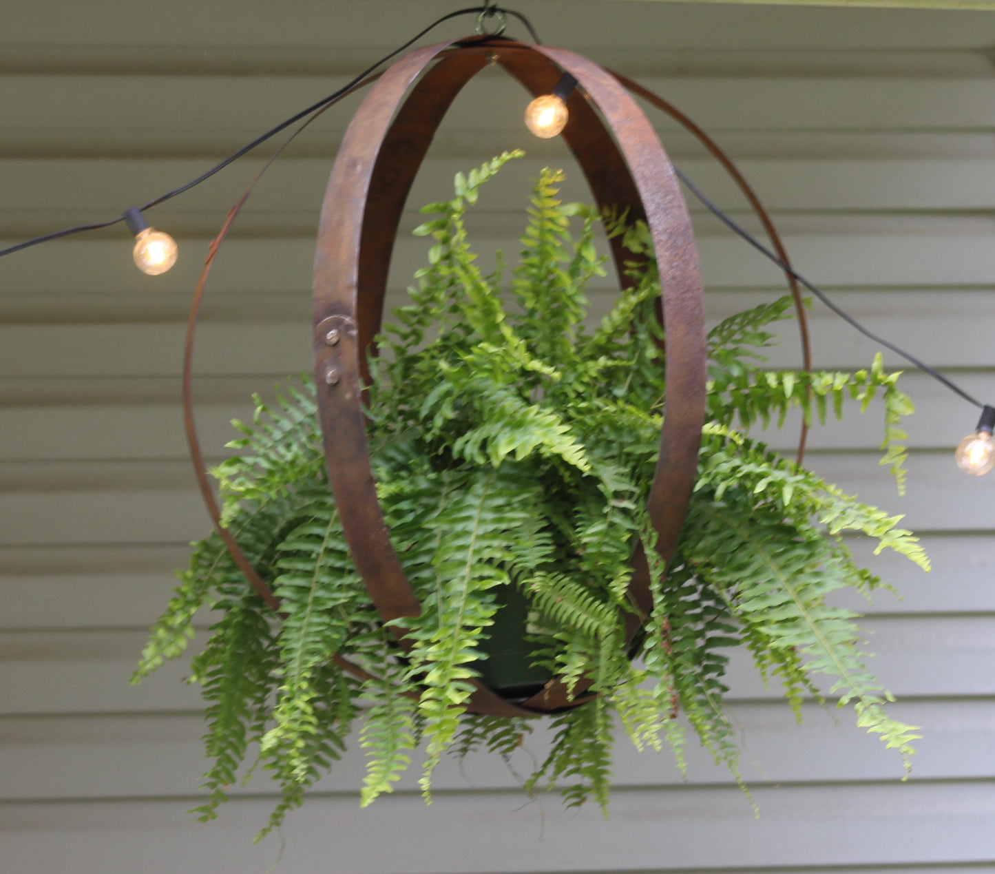 Rustic outdoor hanging plant holder made from reclaimed whiskey barrel rings, crafted by AmishToyBox.com.