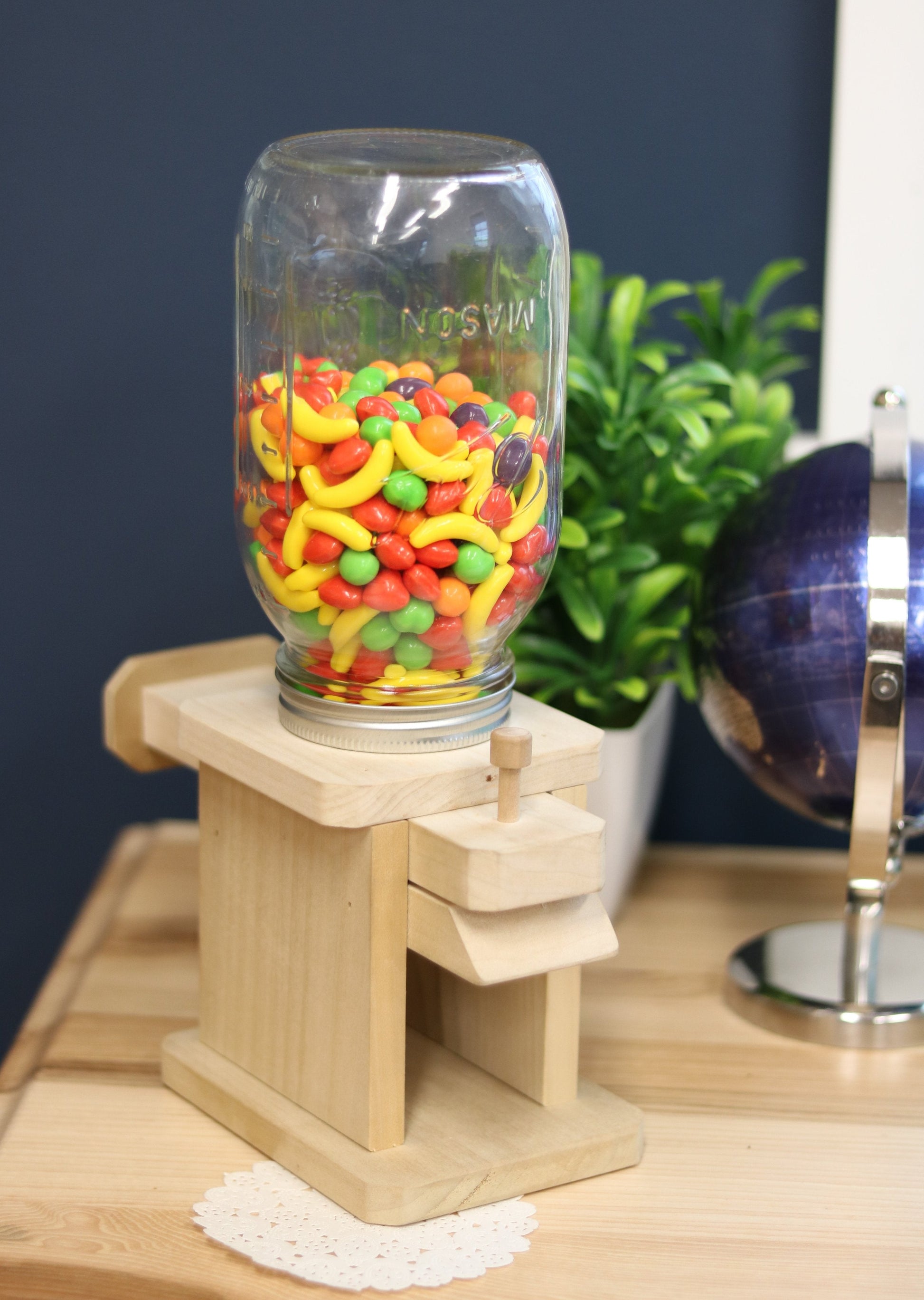 Toy jar candy dispenser from AmishToyBox.com, designed for M&M's, peanuts, or jelly beans, with a clear container and playful design.