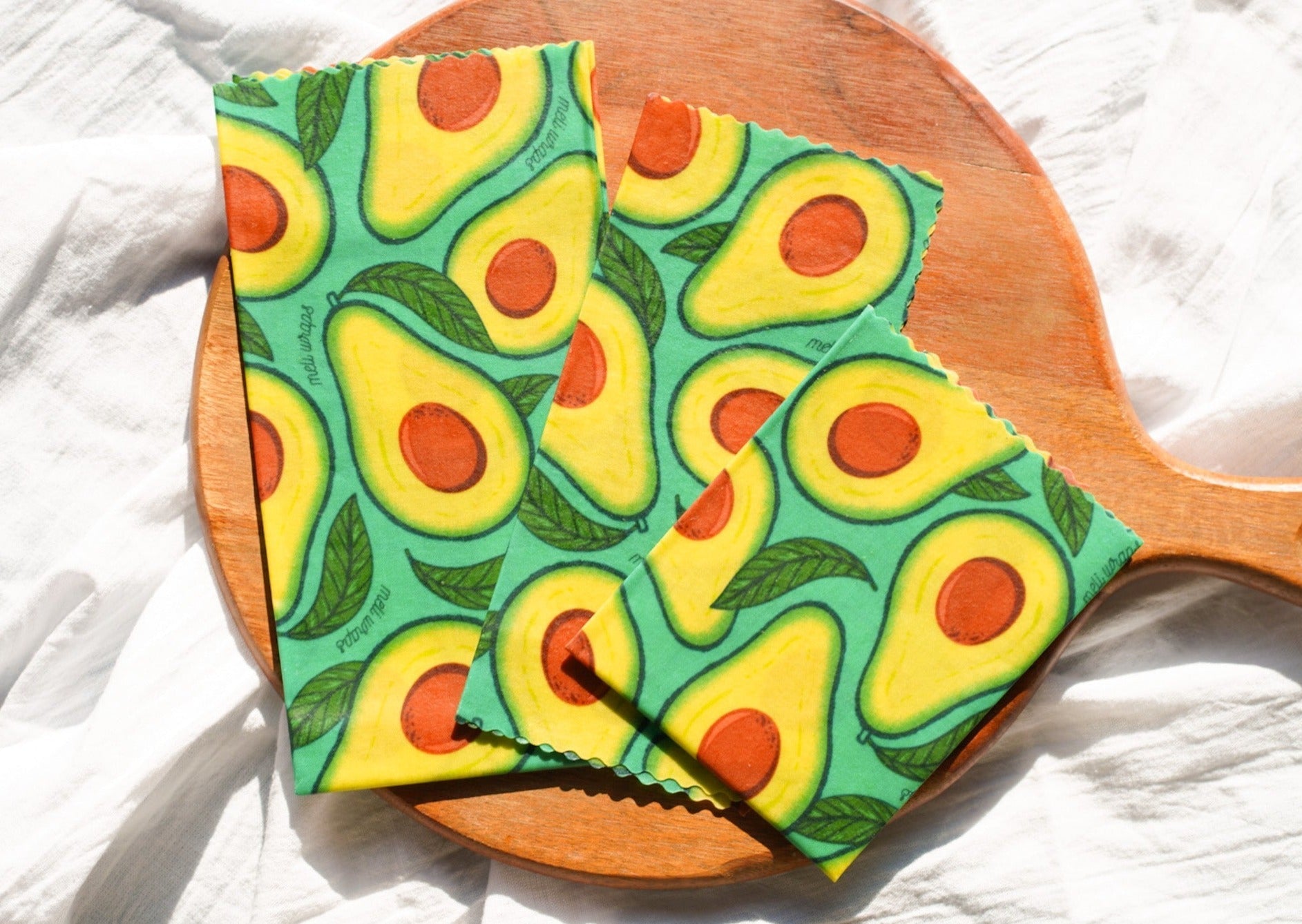 Set of three Meli Wraps beeswax food wraps in avocado print, small, medium, and large sizes for eco-friendly food storage.