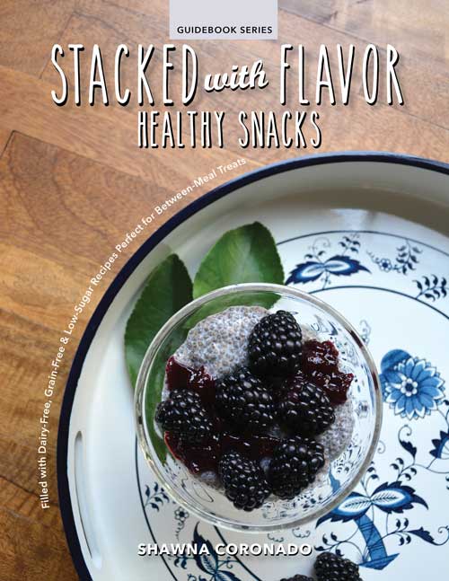 Stacked with Flavor healthy snacks book by Mother Earth News, featuring colorful illustrations and pages about nutritious snack ideas.
