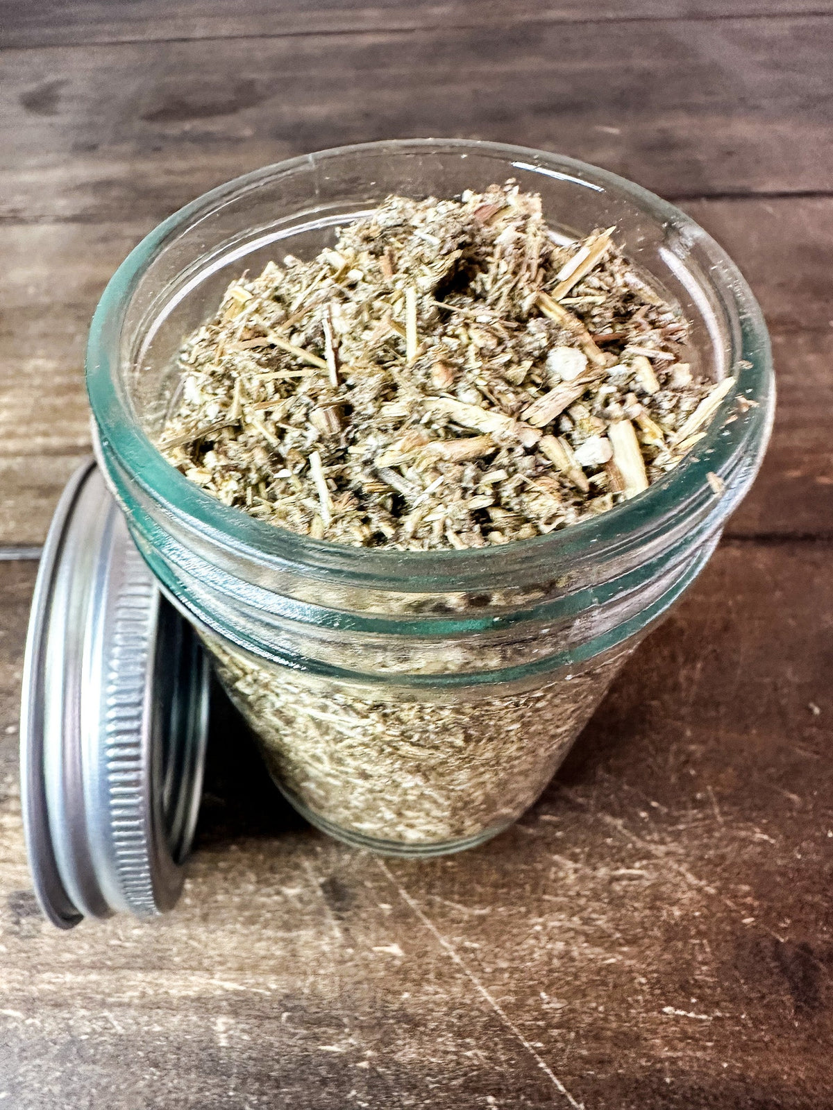 Small jar of dried mugwort herbs in a herbalroseapothecary herb jar, showing the jar's label and herbal contents.