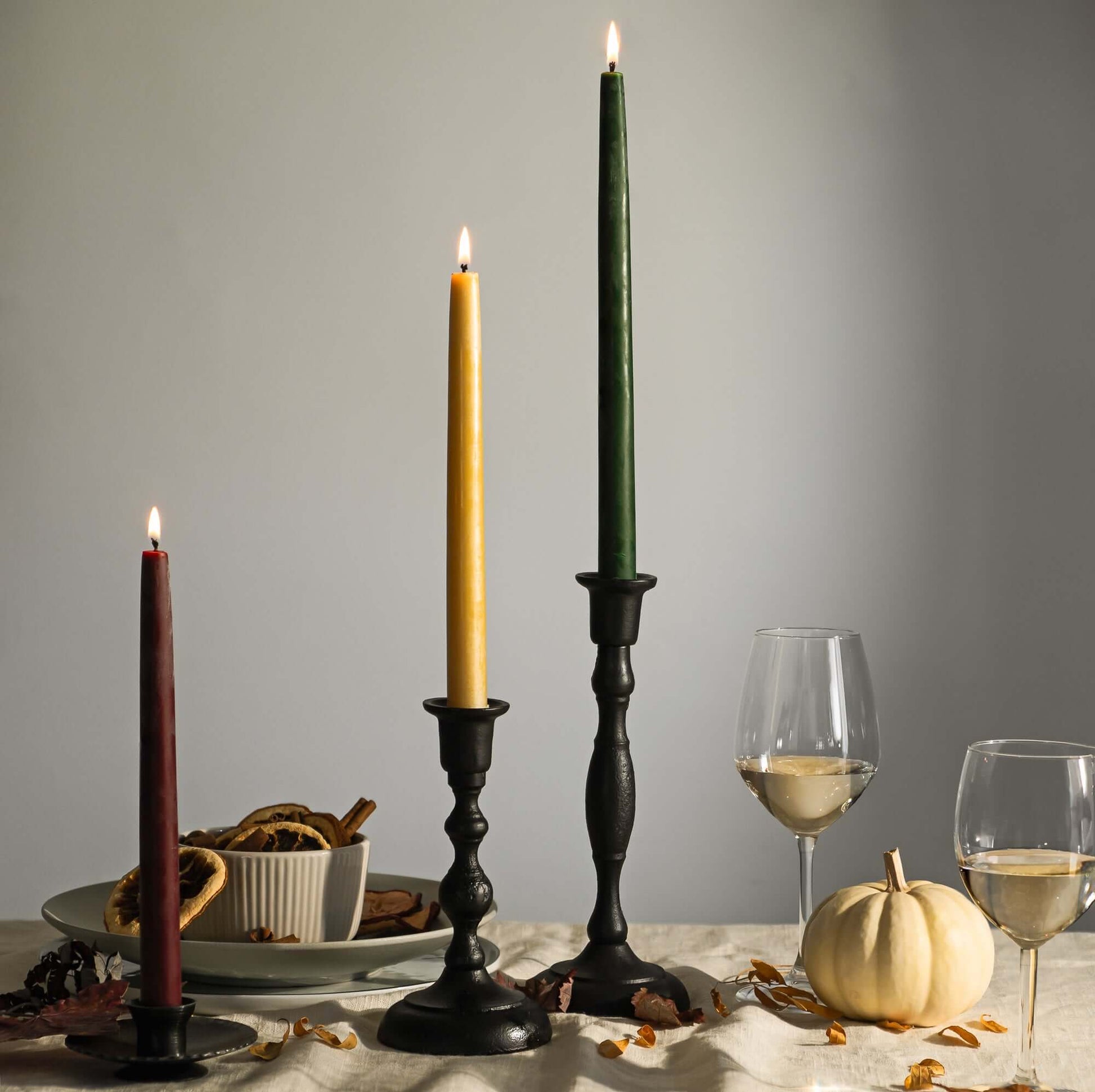 Four pairs of natural beeswax taper candles from Bluecorn Candles displayed in candle holders, showcasing their warm, golden color.