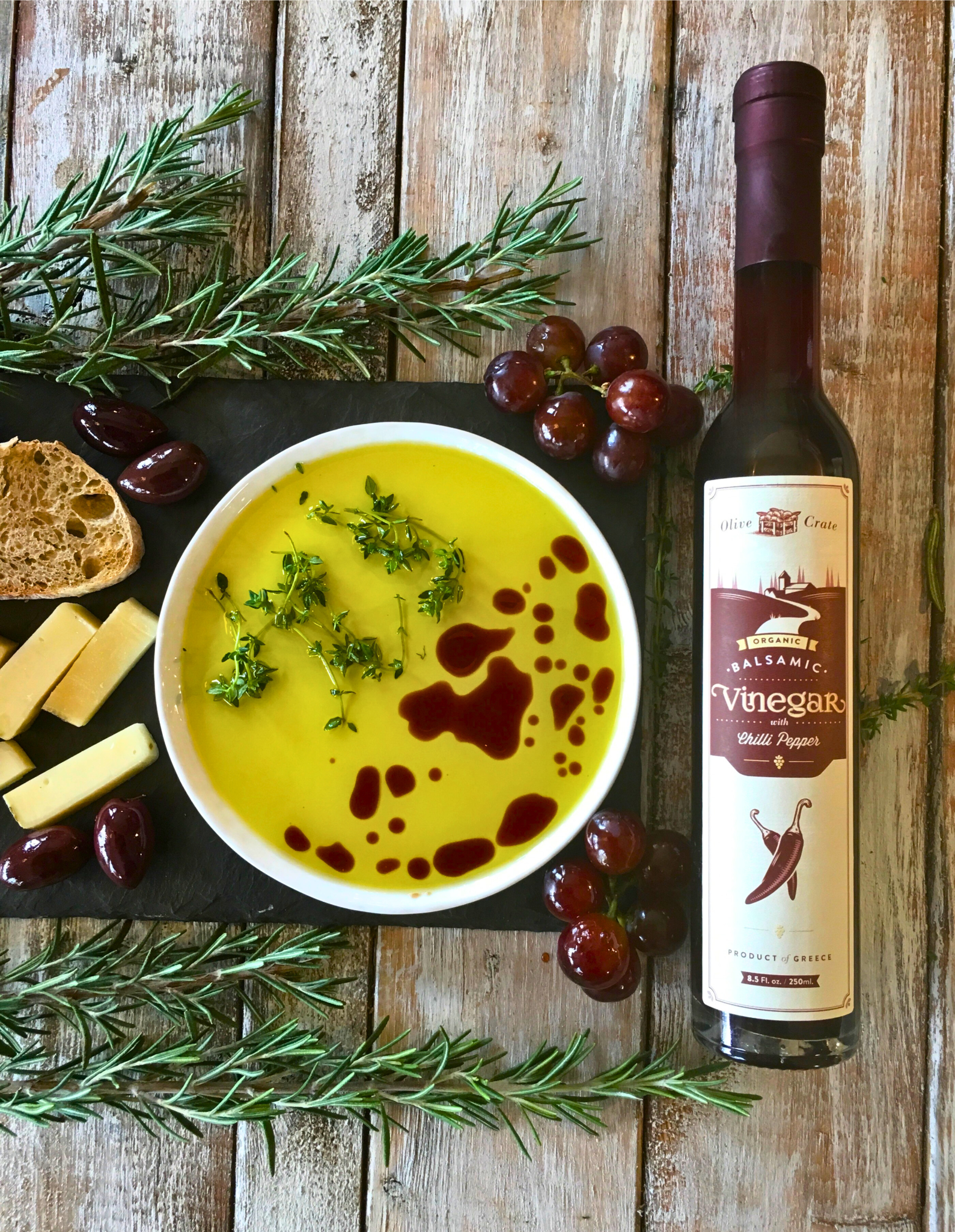Bottle of Olive Crate 100% organic balsamic vinegar with chili pepper, featuring a dark liquid and red chili slices inside.