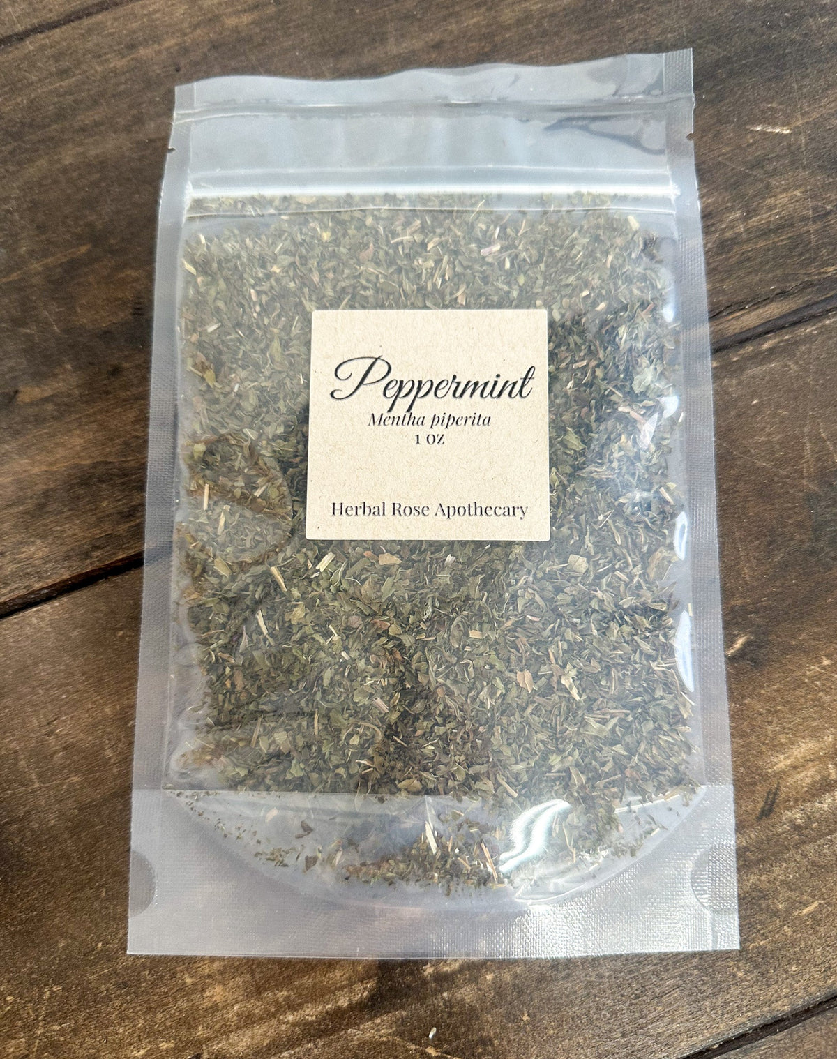Dried peppermint herbs from HerbalRoseApothecary, showing green leaves and stems in a natural, rustic setting.