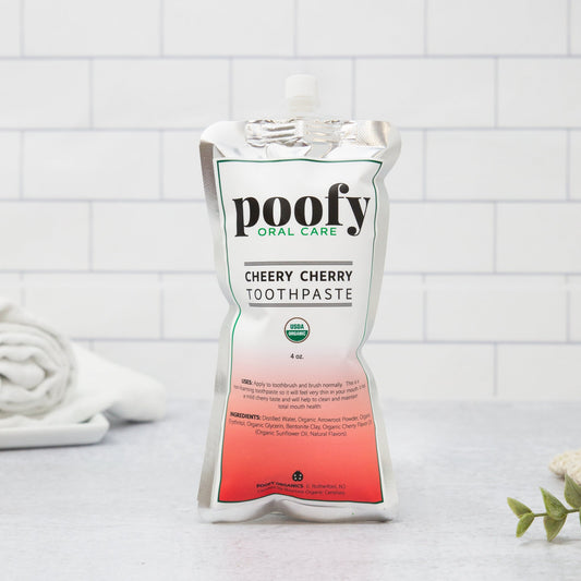 Poofy Organics Cheery Cherry toddler toothpaste in a tube, featuring organic ingredients and colorful cherry-themed packaging.